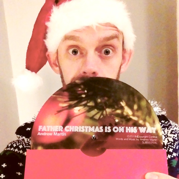 Andrew Martin holding a limited edition 7 inch vinyl edition of his song Father Christmas Is On His Way.